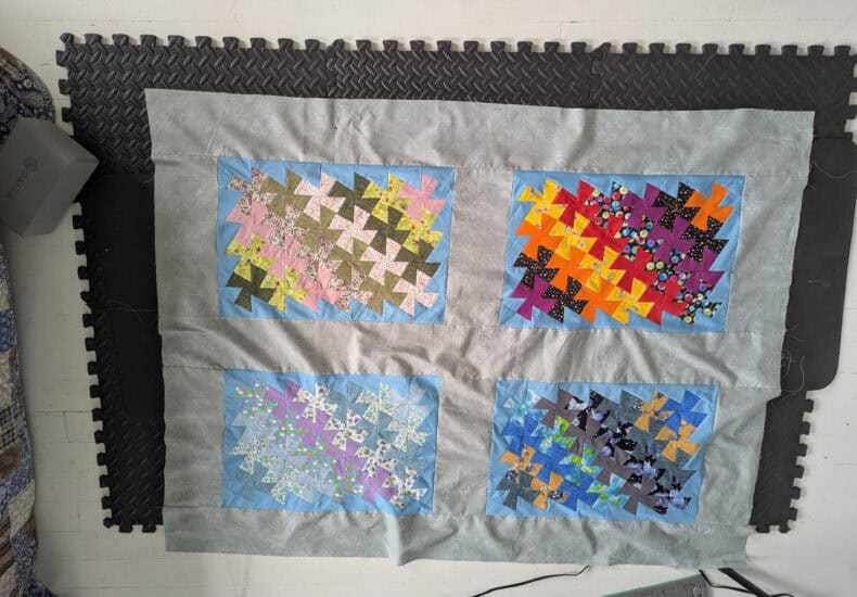 Colorful patchwork quilt with geometric star patterns displayed on a table, showcasing quilting craftsmanship and vibrant fabric choices.